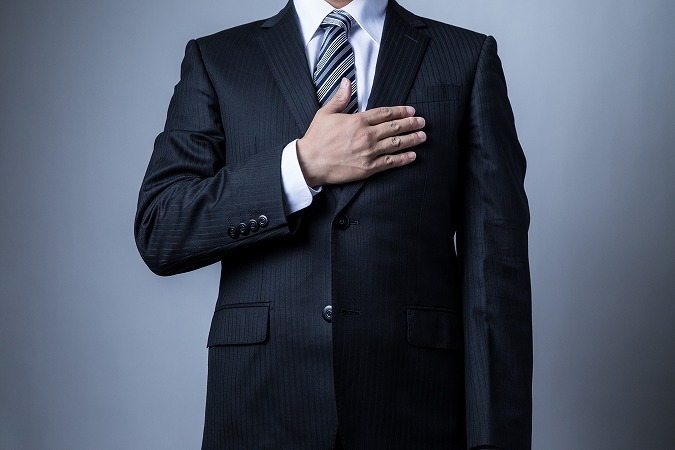 胸に手を当てるスーツ男性
