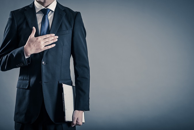 バインダーを持って胸に手を当てる人