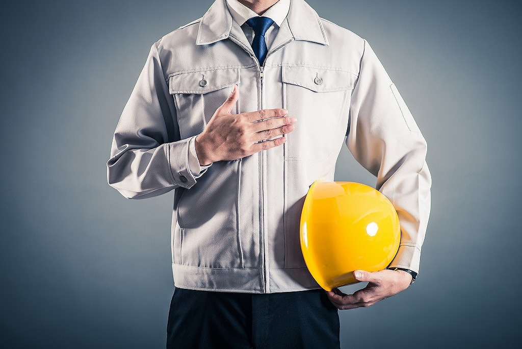 黄色いヘルメットを持って胸に手を当てる男性