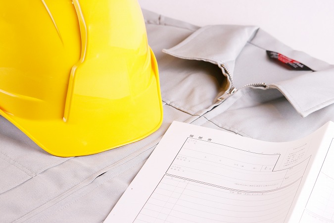 黄色いヘルメットと履歴書と作業着